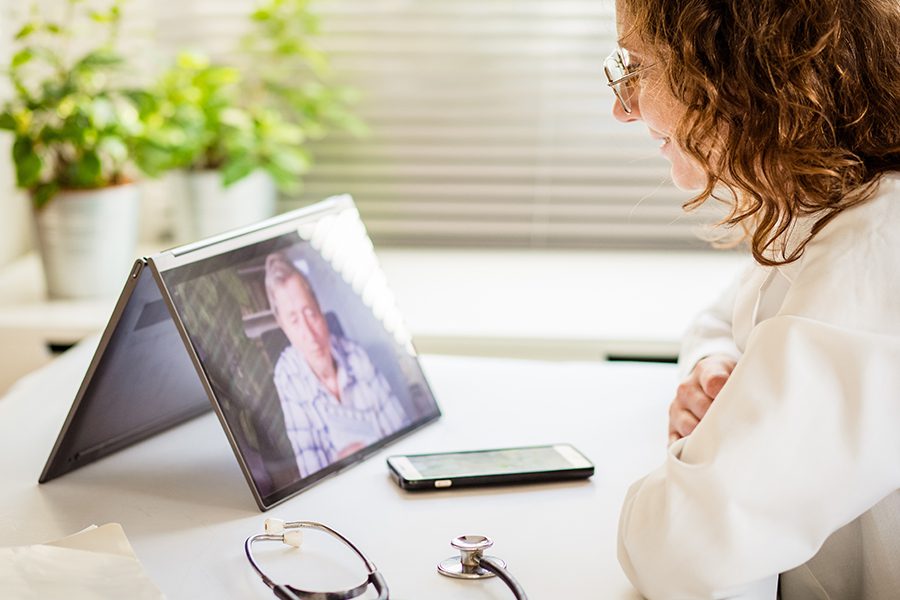 Individual Telemedicine - Doctor Diagnosing Patient Over Video Conference with Tablet in the Office