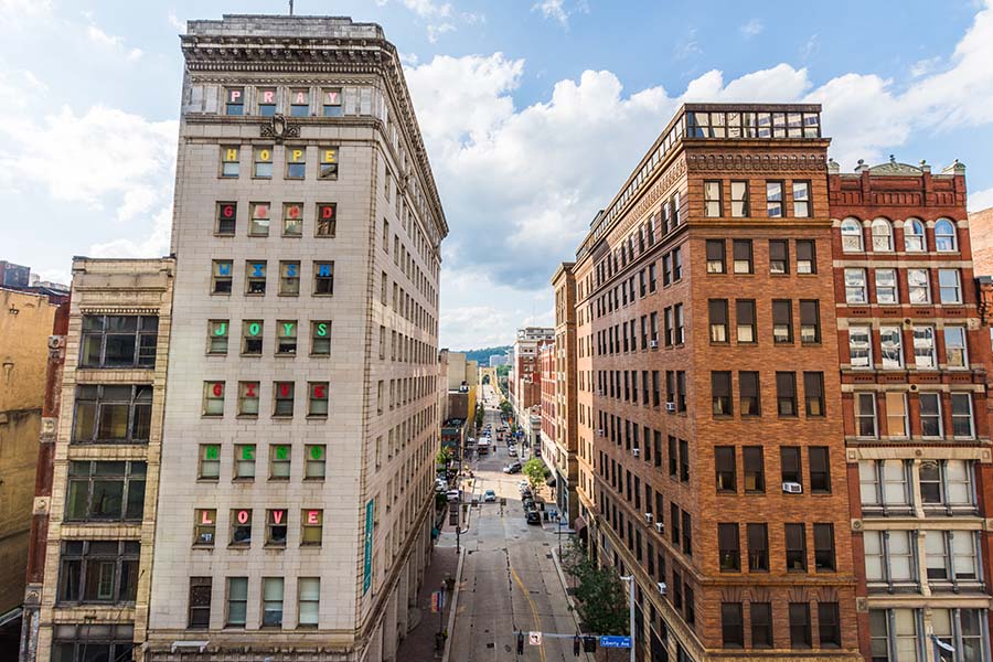 Blog - View of Commercial Buildings and Busy City Street in Downtown Pittsburgh Pennsylvania Against a Cloudy Blue Sky
