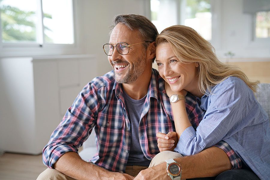 Life and Health Insurance - Closeup Portrait of a Cheerful Older Married Couple Sitting on the Sofa in Their Home